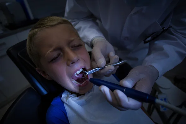 Dentist examining a young patient with tools