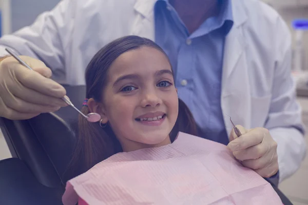 Dentist examining a young patient with tools