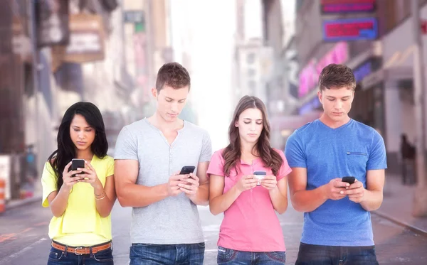 Four people standing and texting on phones