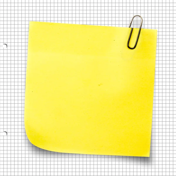 Sticky note with thumbtack against notepad