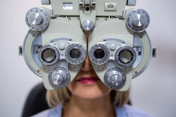 Female patient looking through phoropter during eye examination