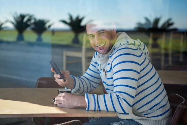 Smiling man using mobile phone in the coffee shop