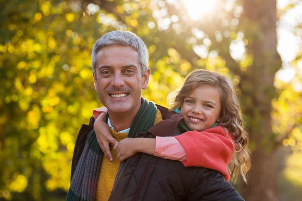 Father piggybacking daughter at park