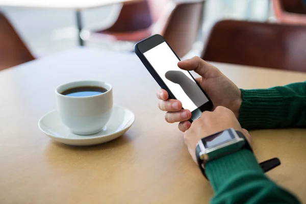 Hand using mobile phone with cup of coffee in table