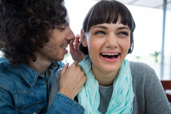 Man whispering in woman s ear