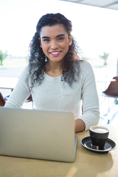 Woman using laptop and a coffee cup
