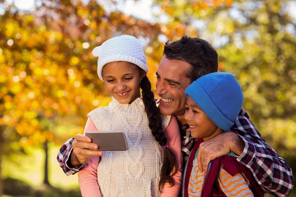 Father with children looking at phone at park