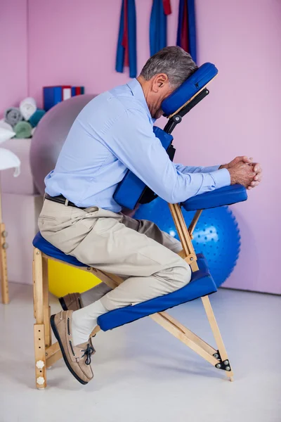 Senior man sitting on massage chair