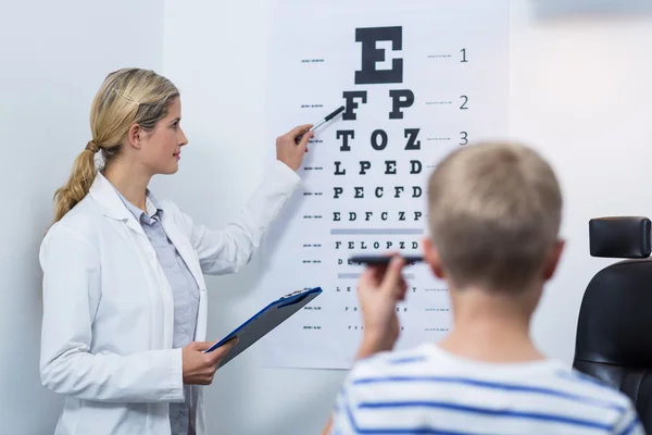 Female optometrist taking eye test of young patient
