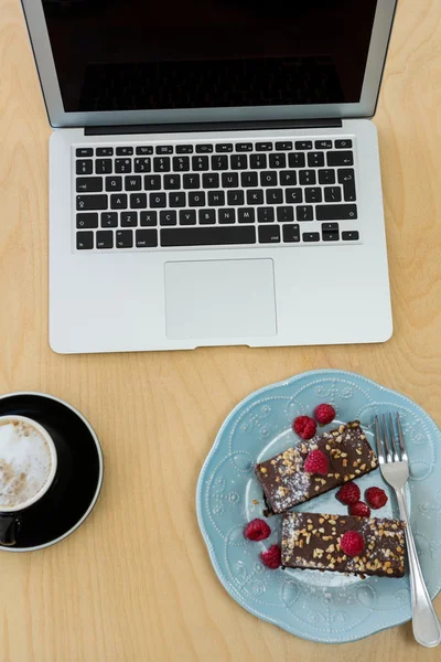 Delicious cakes, cup of coffee and laptop on table