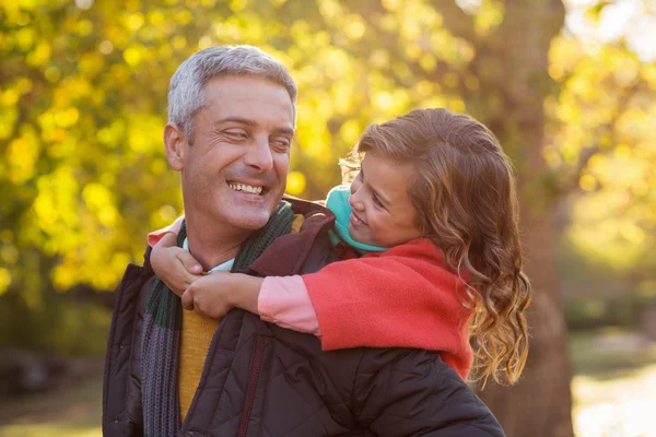 Father piggybacking daughter at park