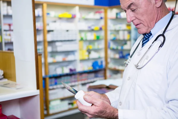Pharmacist holding digital tablet while checking medicine