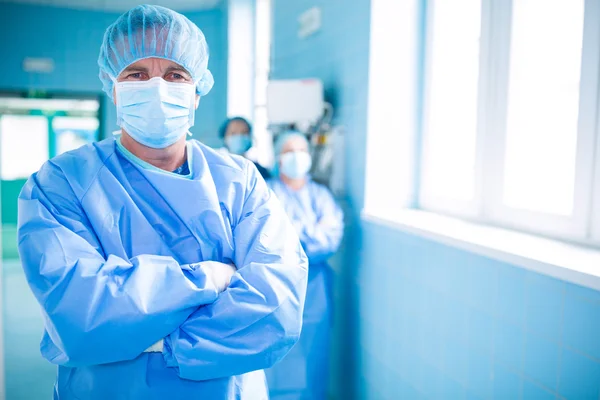 Surgeon standing with arms crossed in corridor
