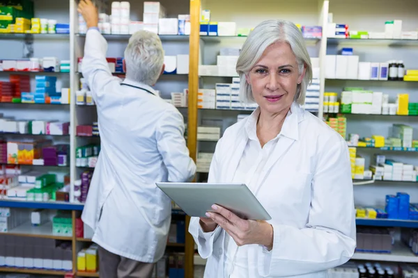 Pharmacist using tablet and co-worker checking medicines