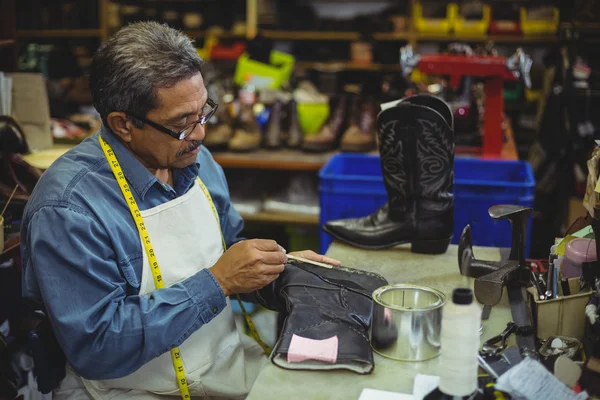 Shoemaker applying glue on shoe