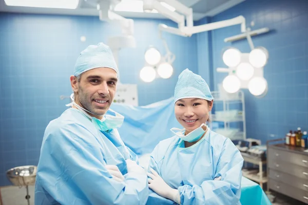 Surgeon and nurse standing with arms crossed