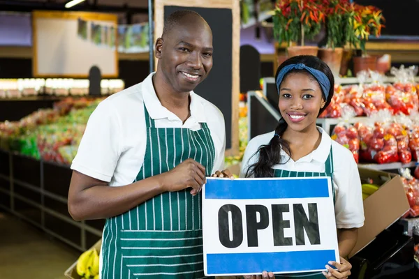 Smiling staffs holding open sign board in organic section