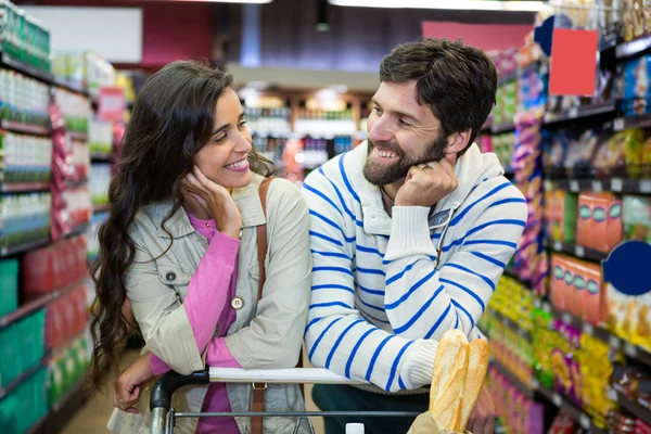 Couple leaning on trolley at supermarket