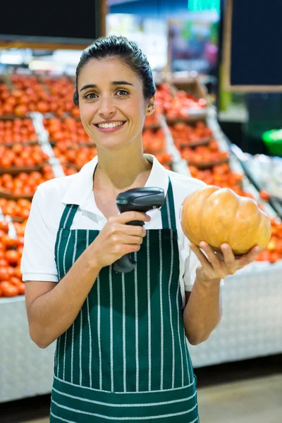 Female staff standing with barcode scanner and pumpkin