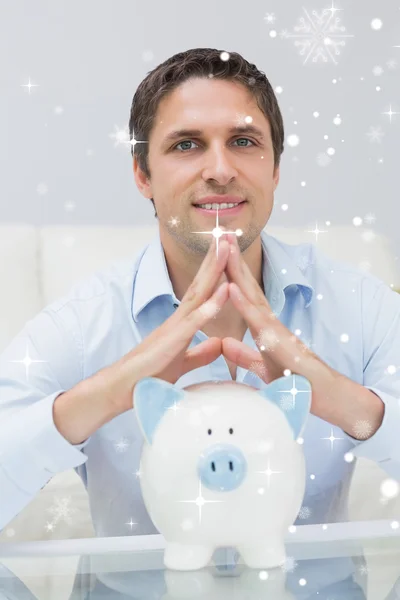 Casual man with piggy bank in living