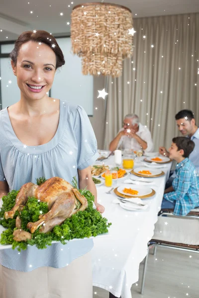 Woman holding chicken roast with family