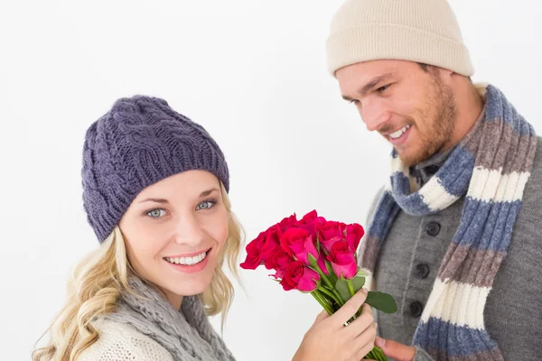 Attractive couple in warm clothing holding flowers