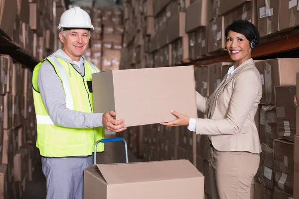 Warehouse worker and manager passing box