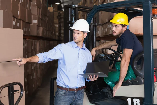 Warehouse manager talking with forklift driver