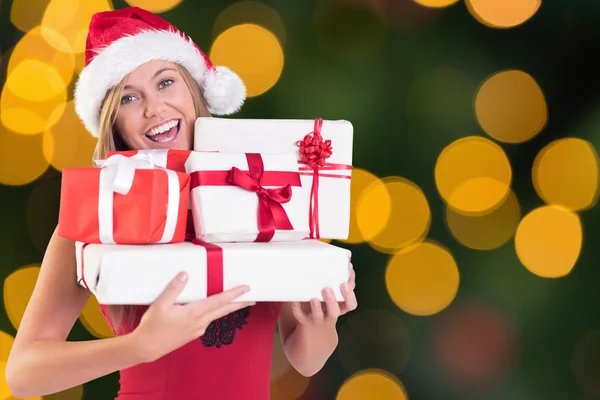 Composite image of festive blonde holding pile of gifts