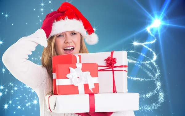 Composite image of festive blonde holding pile of gifts