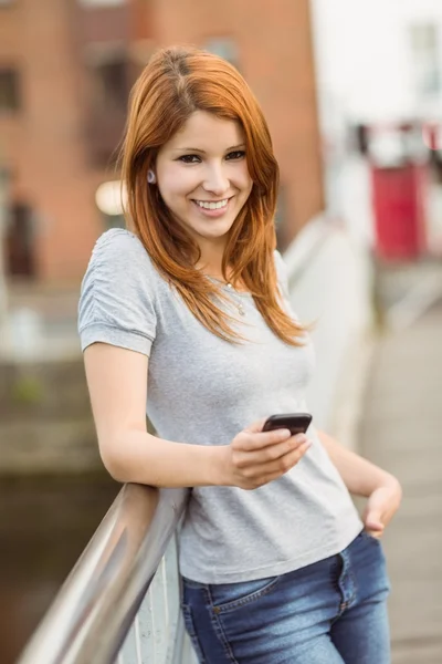 Smiling redhead with her mobile phone texting a message
