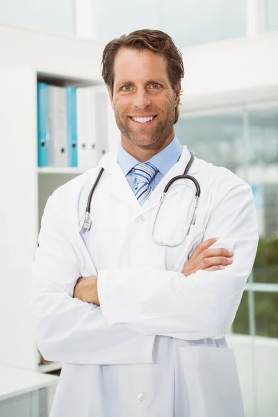Male doctor with arms crossed in medical office