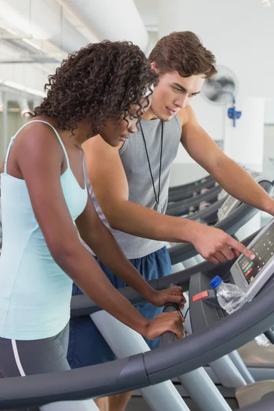 Fit woman on treadmill talking to personal trainer