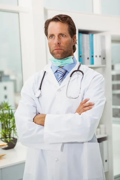 Serious doctor with arms crossed in medical office