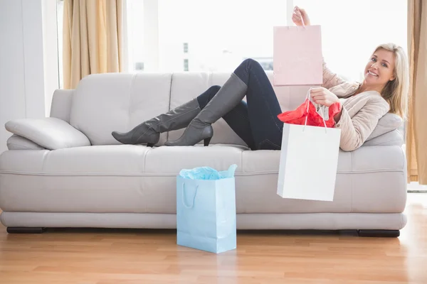 Woman lying on couch with shopping bags