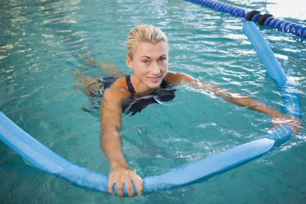 Female swimming with foam roller in pool