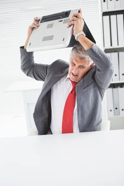 Angry businessman throwing his laptop