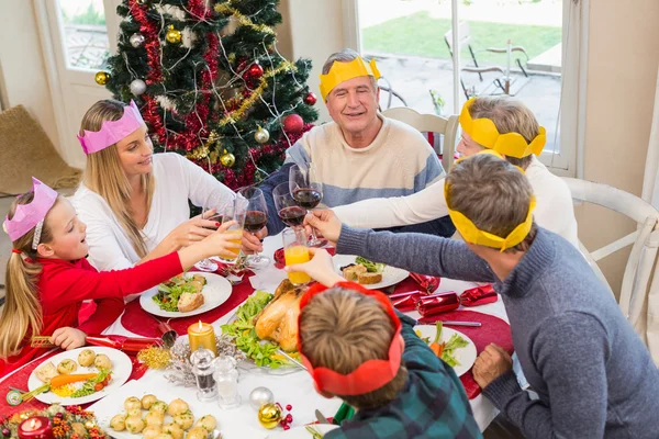 Family in party hat toasting at christmas dinner