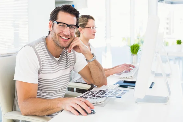 Man wearing glasses sitting at desk looking at camera