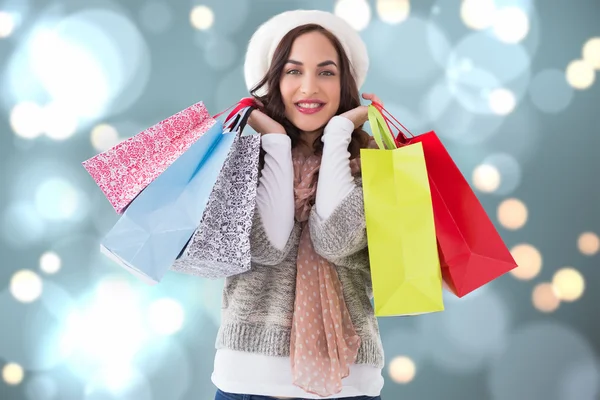 Composite image of brunette in winter clothes with shopping bags