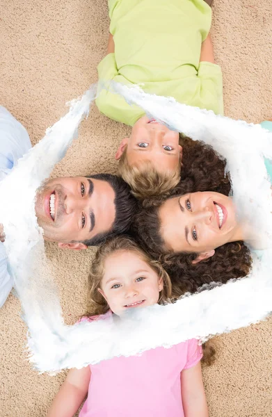 Smiling family lying on the rug in a circle