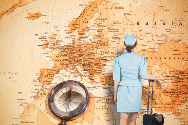 Pretty air hostess leaning on suitcase