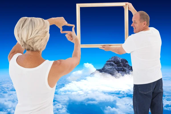 Mature couple hanging up picture frame