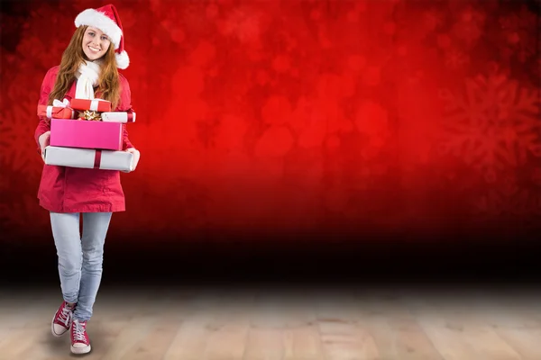 Festive redhead holding pile of gifts