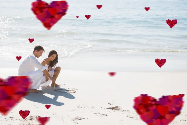 Cute couple drawing a heart in the sand