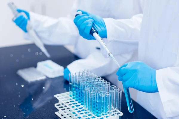 Science students using pipettes to fill test tubes