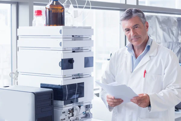 Scientist standing in lab coat holding a document