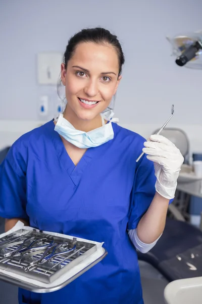 Smiling dentist holding tray and angle mirror