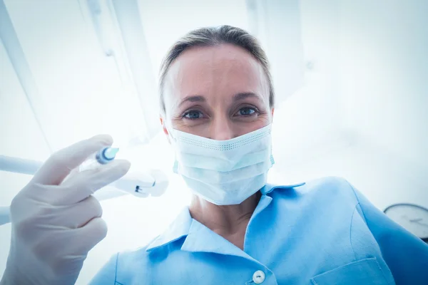 Female dentist in surgical mask holding injection