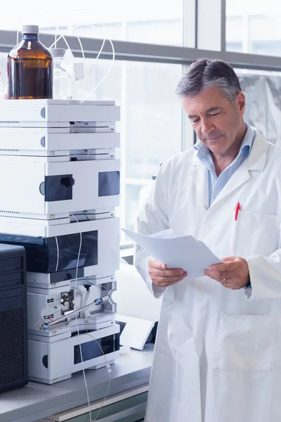 Scientist standing in lab coat reading analysis